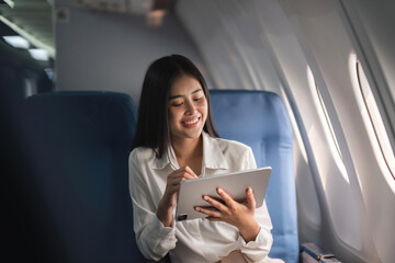 Beautiful asian travel woman watching movie on digital tablet in airplane