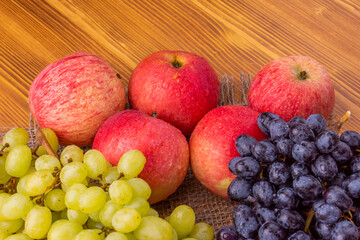Naklejka na ściany i meble Different grapes and apples on a wooden background. Healthy food.