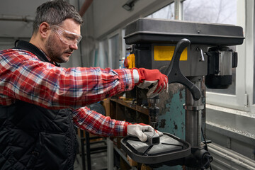 Adult male making hole in steel profile