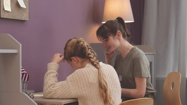 Medium shot of Caucasian female army officer helping her preteen daughter with home assignment