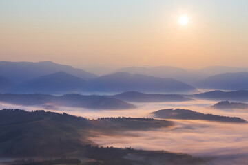 mountain valley in dense mist at the sunrise, early morning mountain landscape