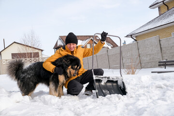 Man removing snow from sidewalk after snowfall. Portrait of man with dog during winter time