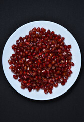 Pomegranate fruit on a white plate. Pomegranate fruit grains.