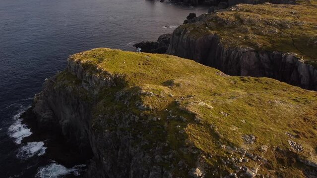 Aerial East Coast revealing shot of waves crashing on high rocky cliffs at Spillars Cove Twillingate Newfoundland Canada.
