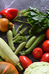 Food cooking background. Fresh rosemary, cilantro, basil, cherry tomatoes, peppers and olive oil, spices herbs and vegetables at black slate table. Food ingredients top view.