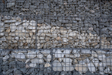 The stones for strengthening the wall are covered with a metal mesh.
