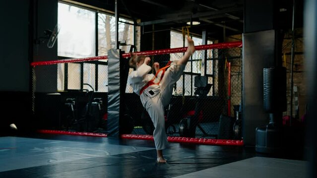 A girl practices karate in a gym A woman in kimono practices movements and poses Martial arts