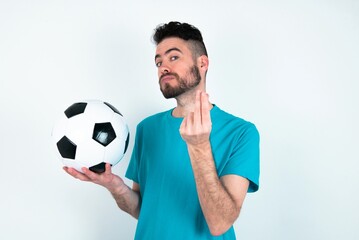 Young man holding a ball over white background doing money gesture with hands, asking for salary...