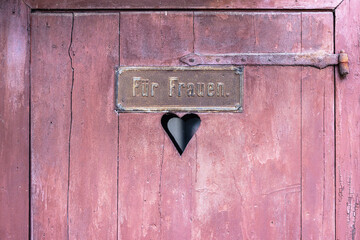 Wooden door of an antique toilet with a sign with the German words Fuer Frauen meaning for women