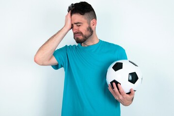 A very upset and lonely Young man holding a ball over white background crying,