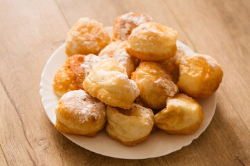 Ruddy donuts sprinkled with powdered sugar in a plate