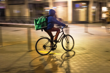 Young cyclist from delivery service is out and about in the city at night