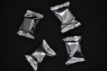 Candy in shiny blisters on a black background. Candy in a shiny package.