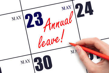 Hand writing the text ANNUAL LEAVE and drawing the sun on the calendar date May 23