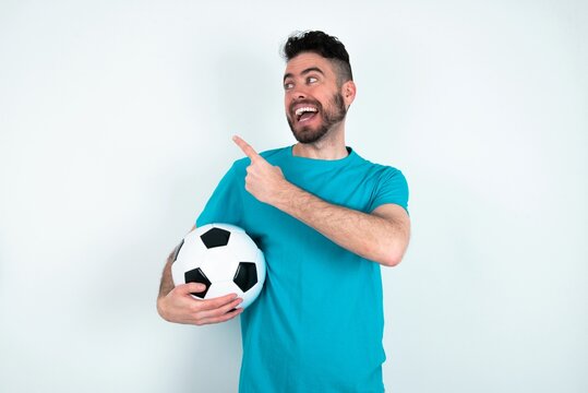 Young man holding a ball over white background glad cheery demonstrating copy space look novelty