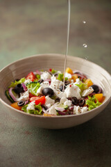 Greek salad of fresh cucumber, tomato, sweet pepper, arugula, red onion, feta cheese and olives with olive oil. Healthy food.