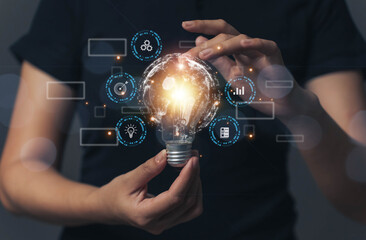 A person holding a light bulb that lights up. Concept of looking for new ideas to work and...