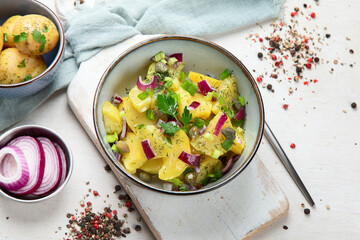 Delicious new potato salad with red onion, capers, greens in a bowl.