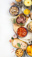 Canned vegetables, beans, fish and fruits in tin cans on a white background. Food stocks.