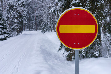 No entry traffic sign next to a snow covered road in winter.