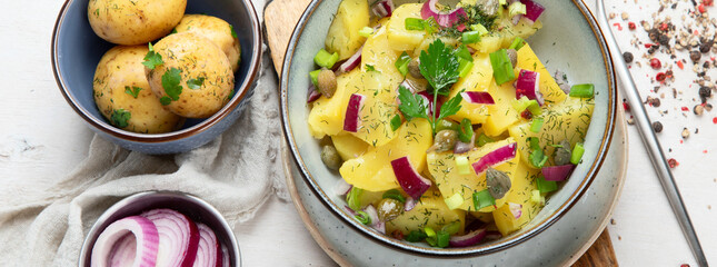 Delicious new potato salad with red onion, capers, greens in a bowl.