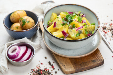 Delicious new potato salad with red onion, capers, greens in a bowl.