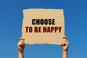 Choose to be happy text on box paper held by 2 hands with isolated blue sky background. This...