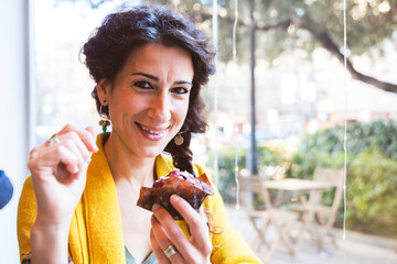 Woman looking at camera smiling with a cupcake in her hand