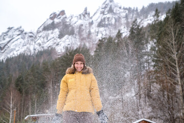 Fototapeta na wymiar Beauty Girl smile in winter mountains Outdoor. Flying Snowflakes. Beauty young woman Having Fun in Winter Park. Good mood while spending time outdoors on snowy winter day in mountains