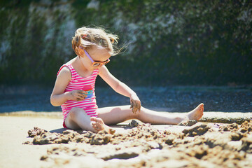 Preschooler girl playing on the sand beach at Atlantic coast of Normandy, France