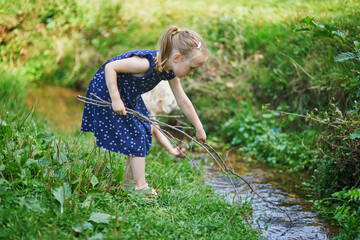 Preschooler girl playing with a twig like with fishing rod