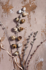 Table Easter decor set with quail eggs, beige ribbon and willow branches on wooden vintage table.