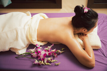 Obraz na płótnie Canvas Asian woman enjoying back massage with scrub salt and cream in massage spa salon. Young girl in spa massage. Healthy treatment concept.