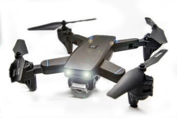 dark quadrocopter on a white background with glowing headlights	
