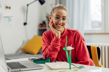 A cute college student is working on her science project and looking at the camera