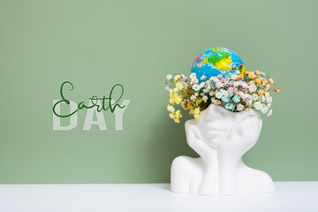Creative plaster vase head-shape with flowers and world globe. Save the planet, Earth day concept