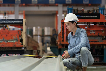 Metalwork manufacturing in plant. Female factory worker inspecting quality galvanized sheet or...