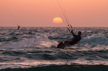 Bat Yam, Israel - May 18, 2020: People ride a Kiteboarding during the sunset. Mediterranean sea