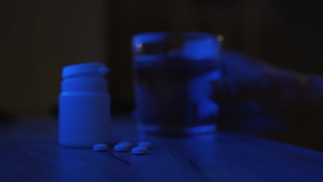 Man drinking sleeping pills late at night, close-up