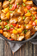 Delicious one pot of beef with vegetables in its own juice close-up in a saucepan on a wooden table. Vertical top view from above