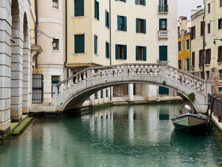 Fototapeta na wymiar Romantische alte Brücke in Venedig vor einem modernen Gebäude