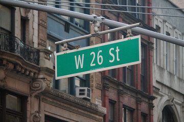 Green big West 26th Street sign hanging on a arch pole in the streets of midtown Manhattan