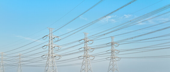 Looking up steel power pylons construction with high voltage cables against blue sky