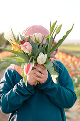 Young teenager girl hiding behind a bunch of tulips. Sunset outdoor scene, family outdoor activity time - 587054022