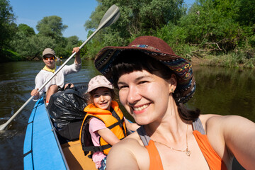 Man and woman couple, baby is sleeping, selfies are happy in family kayak trip rowing boat on the...