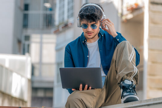 young man on the street with laptop and headphones