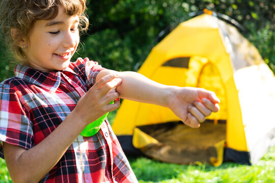 Girl uses a remedy for mosquitoes and biting insects in nature. Protection of the skin from tick bites, gadflies, blood-sucking pests, a means for children without allergens for outdoor camping