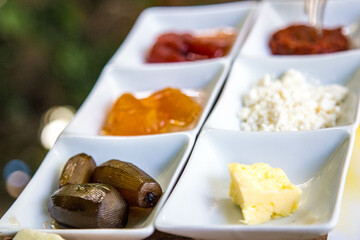 fragment of Turkish breakfast on a plate: cheese, butter, dates, jam, honey