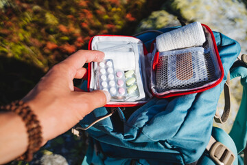 An open first-aid kit with medicines for a hike, a set of pills for vomiting, camping equipment, a...