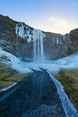 Half frozen waterfall awakens in Iceland